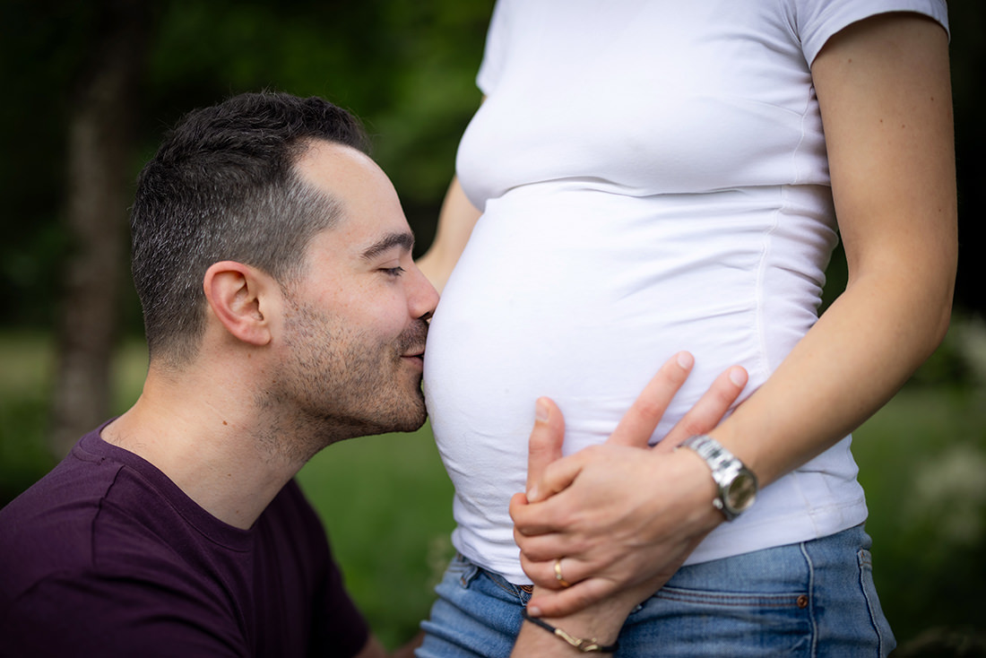 Detailbild Kuss auf Babybauch während eines Outdoor Shootings im Schwarzwald.